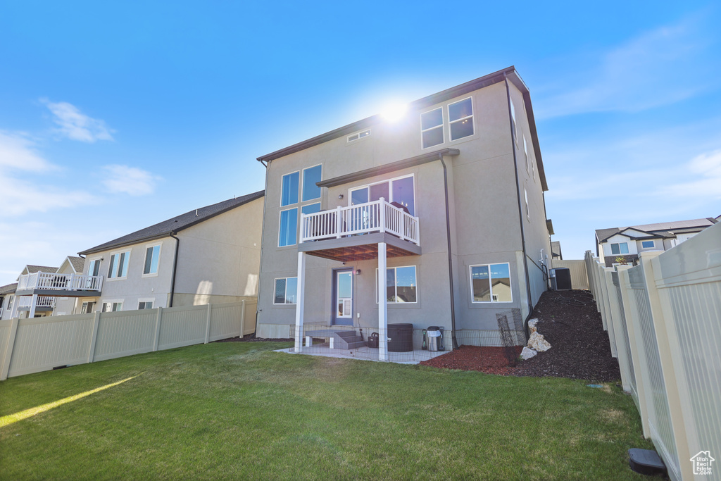 Rear view of house featuring stucco siding, a balcony, and a patio area