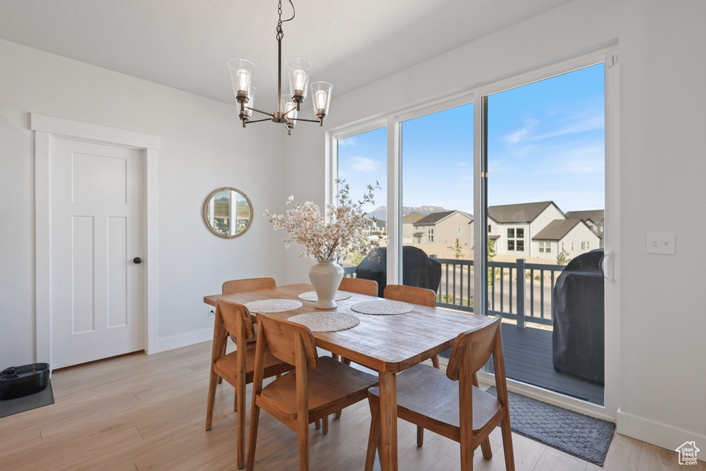 Dining room with a chandelier, baseboards, light wood-style flooring, and a residential view