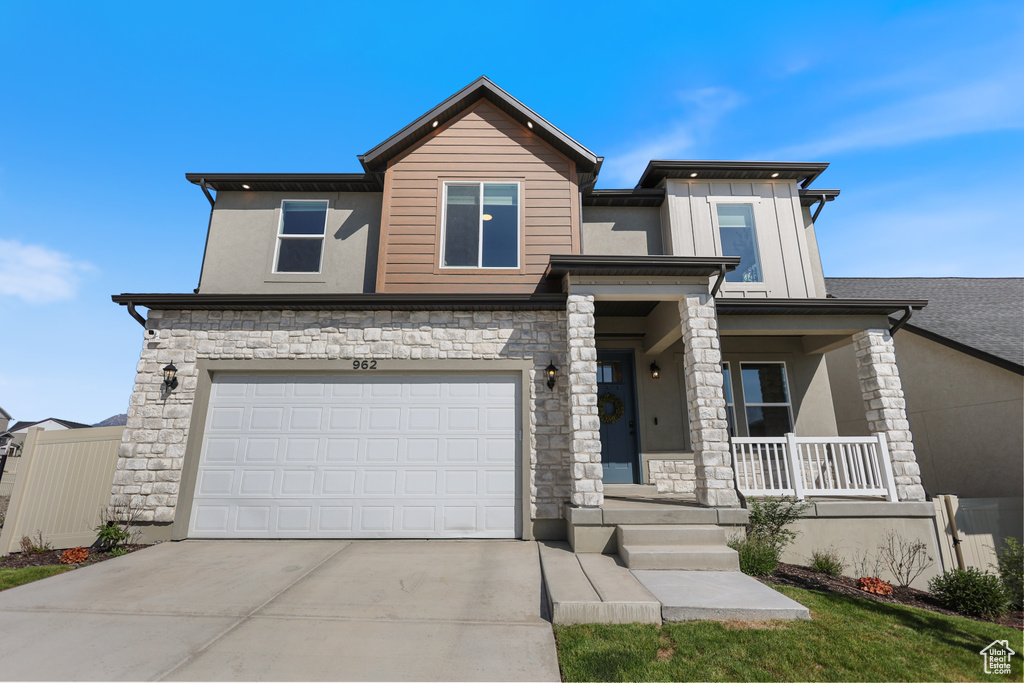 View of front of house with a porch, concrete driveway, stone siding, and an attached garage