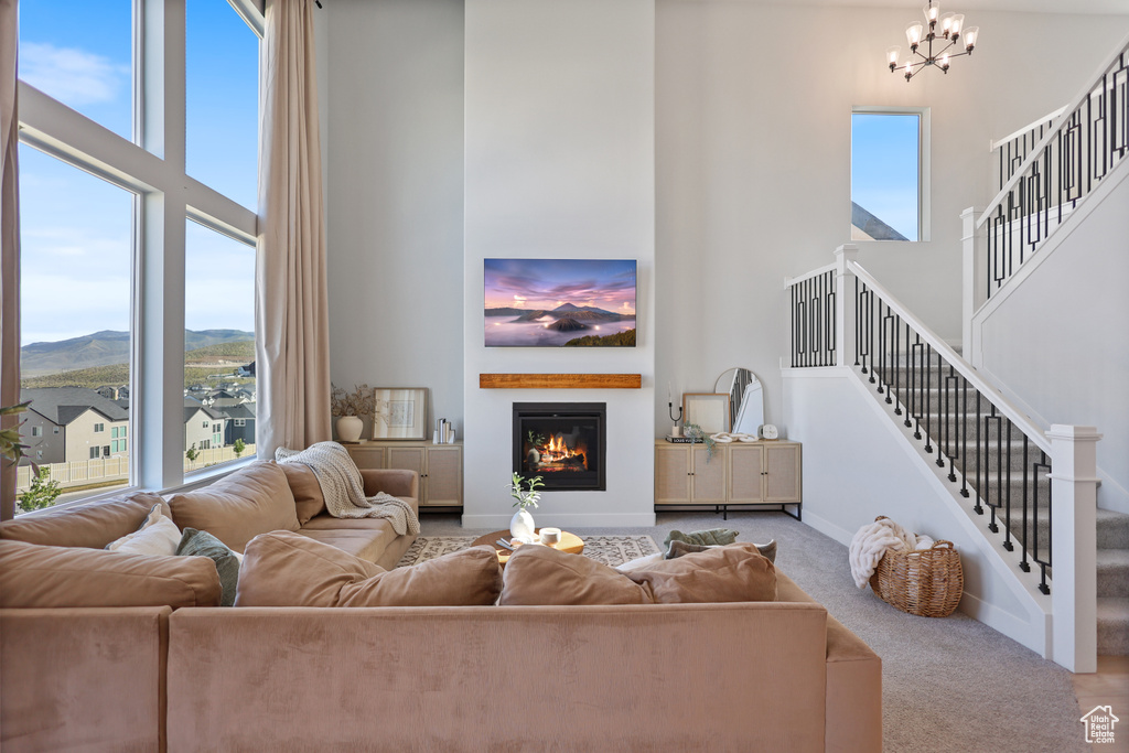Living room featuring a high ceiling, plenty of natural light, a chandelier, stairway, and a mountain view