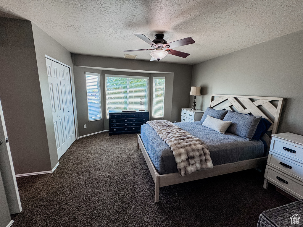Bedroom featuring carpet flooring, a textured ceiling, ceiling fan, a closet, and baseboards