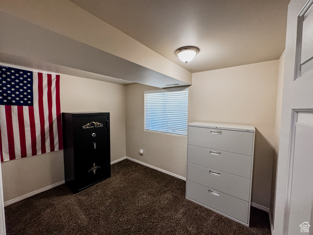 Unfurnished bedroom featuring dark carpet and baseboards