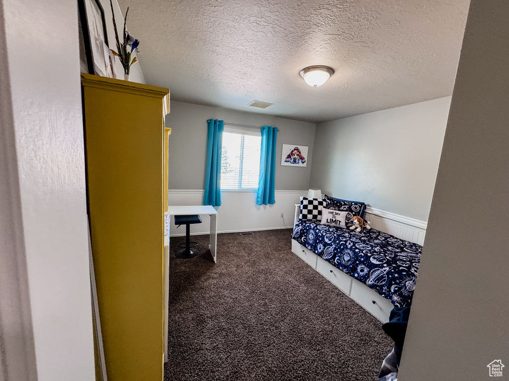 Bedroom featuring a textured ceiling and dark carpet