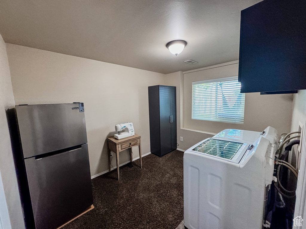 Laundry area featuring washing machine and clothes dryer, dark carpet, and baseboards