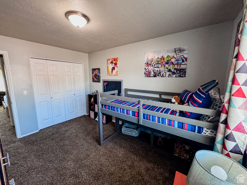 Bedroom with carpet floors, a textured ceiling, and a closet