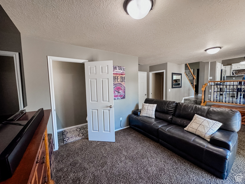 Living room featuring carpet flooring, stairway, a textured ceiling, and baseboards