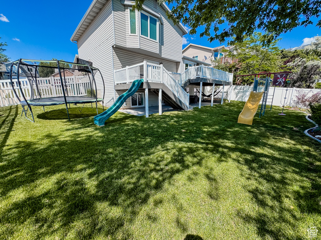 Back of house featuring a trampoline and a playground