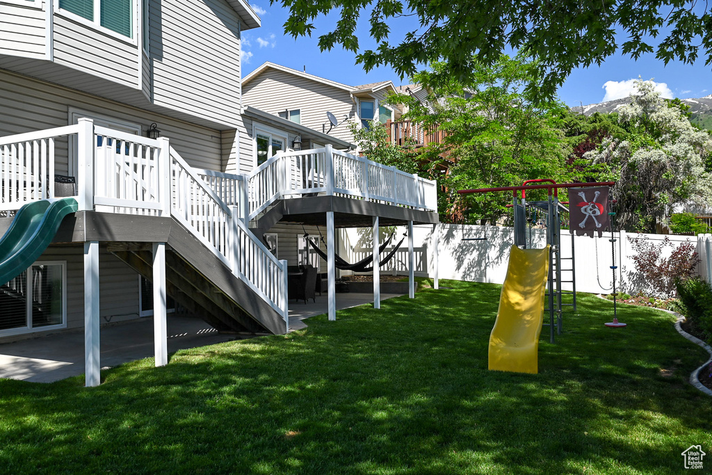 View of yard with a playground, a wooden deck, and stairs