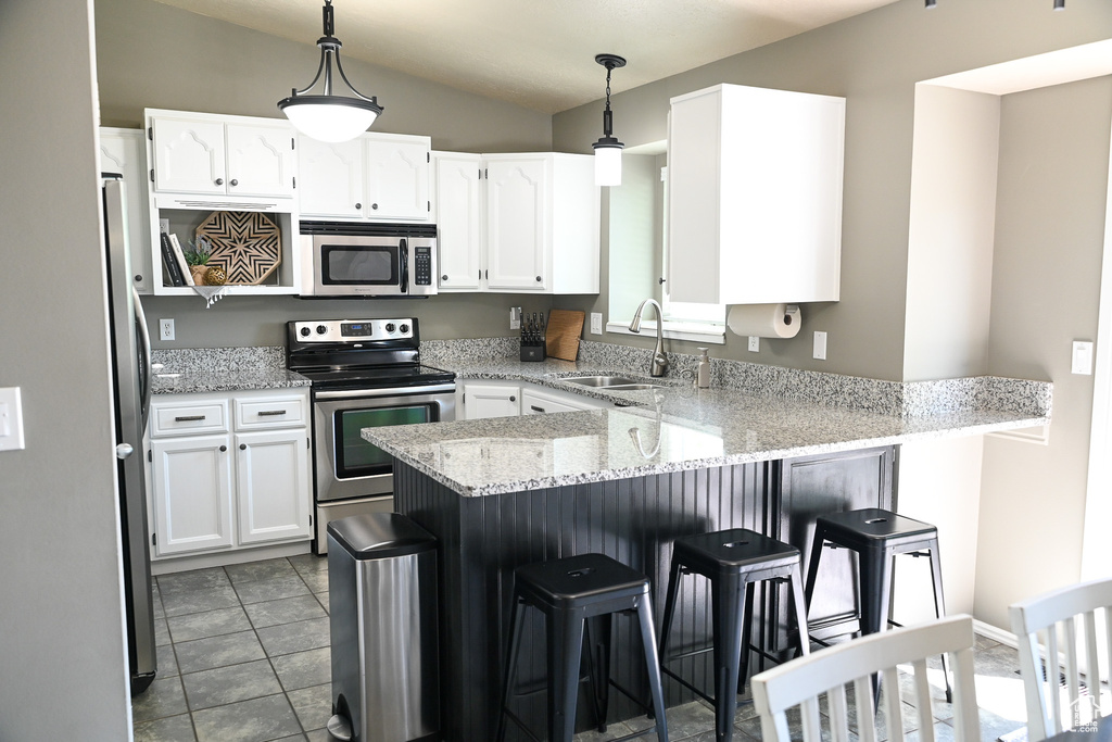Kitchen featuring appliances with stainless steel finishes, a sink, a peninsula, and white cabinetry