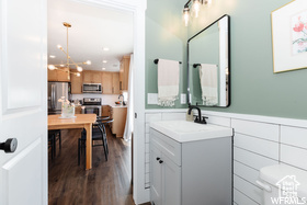 Bathroom featuring vanity, wood finished floors, a wainscoted wall, and toilet