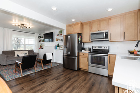 Kitchen with stainless steel appliances, light brown cabinets, a sink, light countertops, and dark wood finished floors