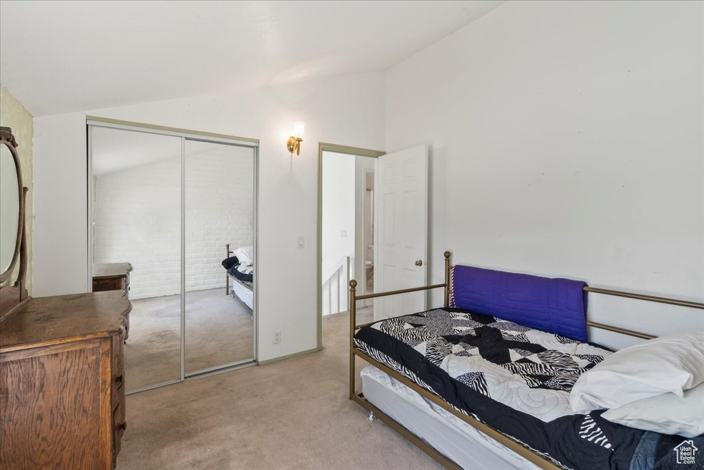 Carpeted bedroom featuring vaulted ceiling and a closet
