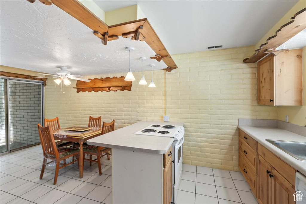 Kitchen featuring white appliances, a ceiling fan, light tile patterned floors, brick wall, and light countertops