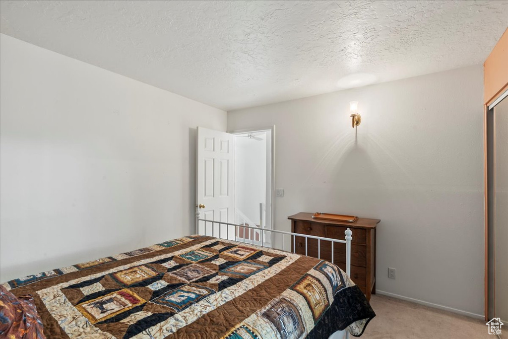 Bedroom featuring light carpet and a textured ceiling