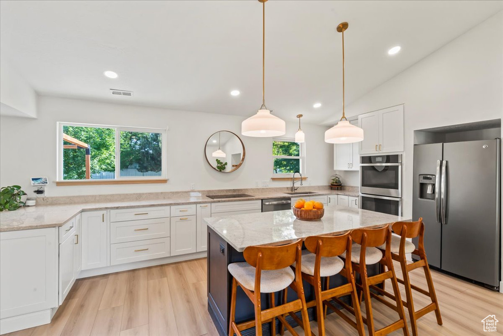 Kitchen with appliances with stainless steel finishes, a sink, white cabinets, light stone countertops, and recessed lighting