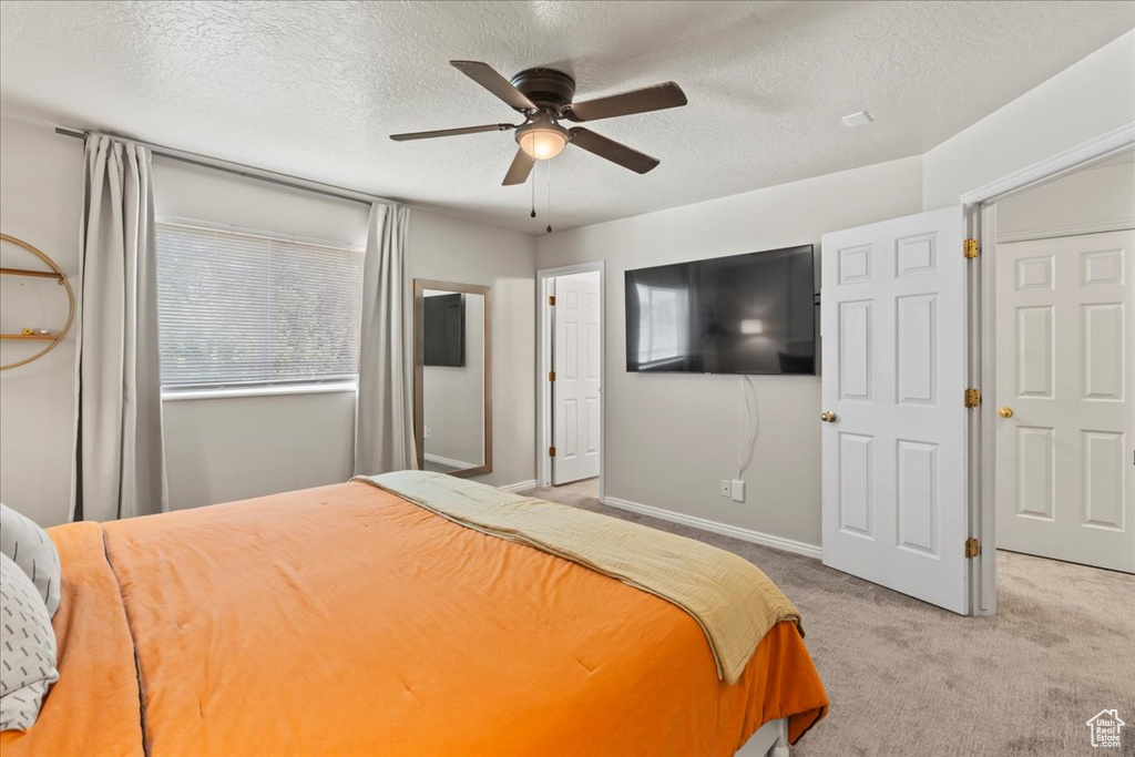 Carpeted bedroom with a textured ceiling, ceiling fan, and baseboards