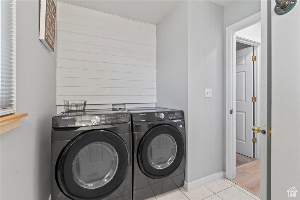 Laundry area featuring washing machine and dryer and light tile patterned floors