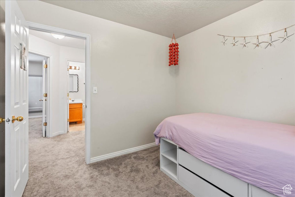 Bedroom featuring light colored carpet, baseboards, and a textured ceiling