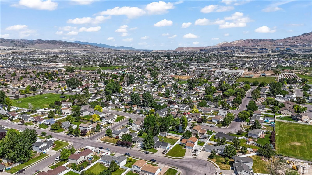 Aerial view of property and surrounding area featuring a mountainous background and nearby suburban area