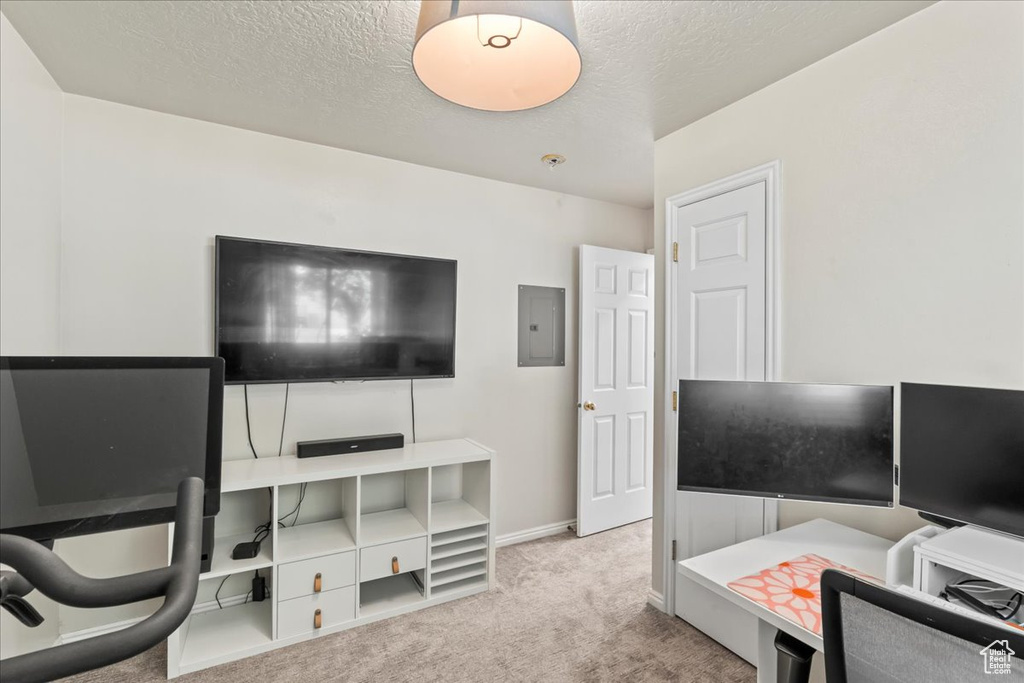 Carpeted home office featuring a textured ceiling, electric panel, and baseboards