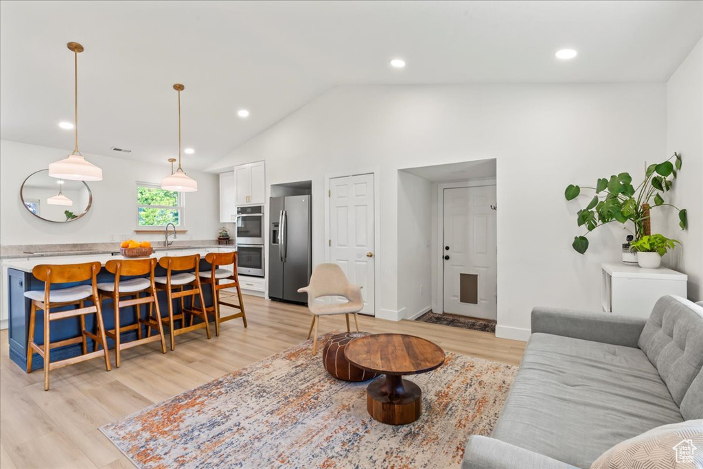Living room featuring light wood finished floors, vaulted ceiling, recessed lighting, and baseboards