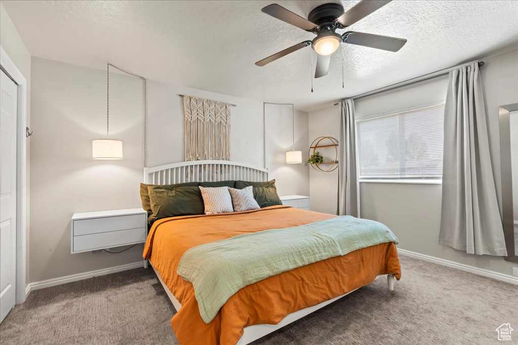 Carpeted bedroom featuring a textured ceiling, baseboards, and ceiling fan