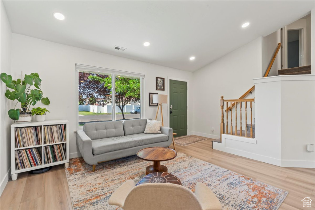 Living area with stairs, wood finished floors, baseboards, and recessed lighting