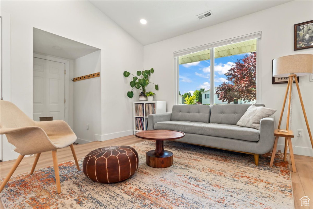 Living room with wood finished floors, baseboards, vaulted ceiling, and recessed lighting