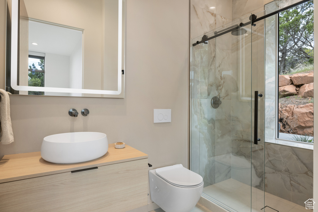 Bathroom featuring a marble finish shower, toilet, and vanity