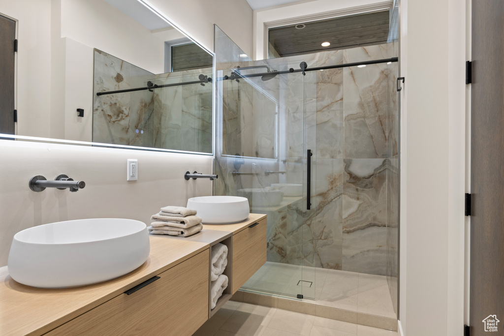 Full bath with a marble finish shower and double vanity