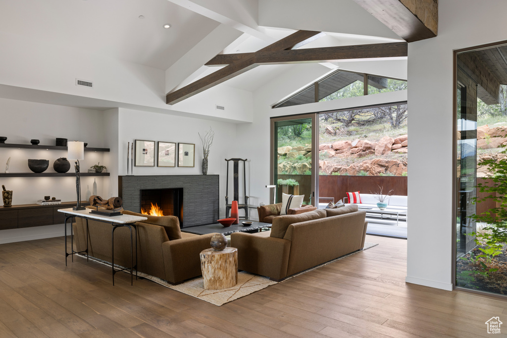 Living area with a fireplace, hardwood / wood-style flooring, beam ceiling, and high vaulted ceiling