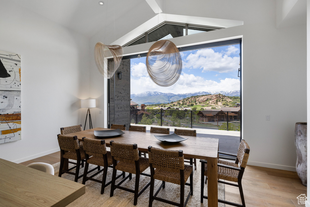 Dining area featuring light wood-style flooring, vaulted ceiling, baseboards, and a mountain view