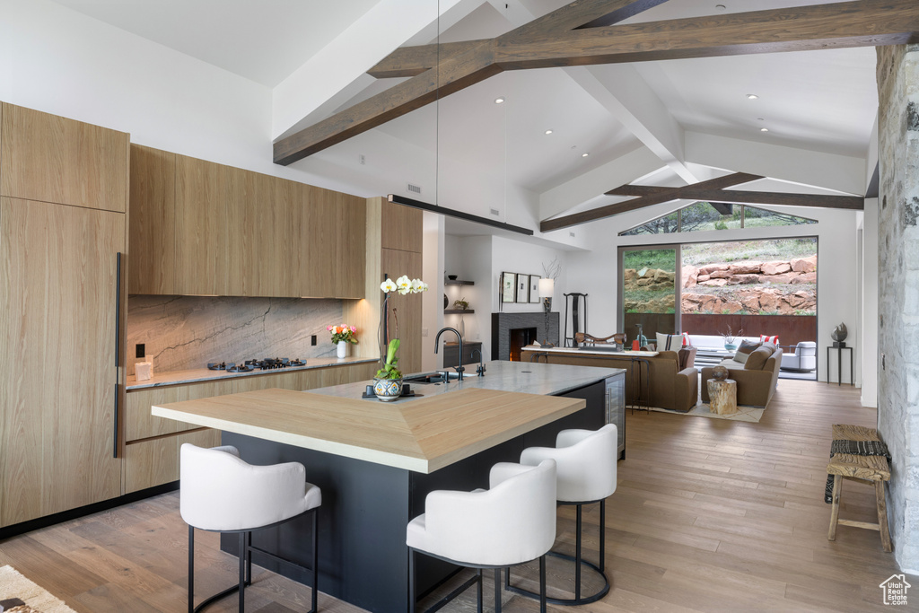 Kitchen with modern cabinets, beamed ceiling, open floor plan, a kitchen breakfast bar, and high vaulted ceiling