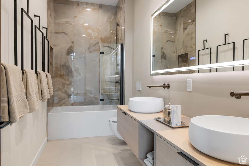 Full bath with double vanity, shower / bathtub combination, toilet, and tile patterned flooring
