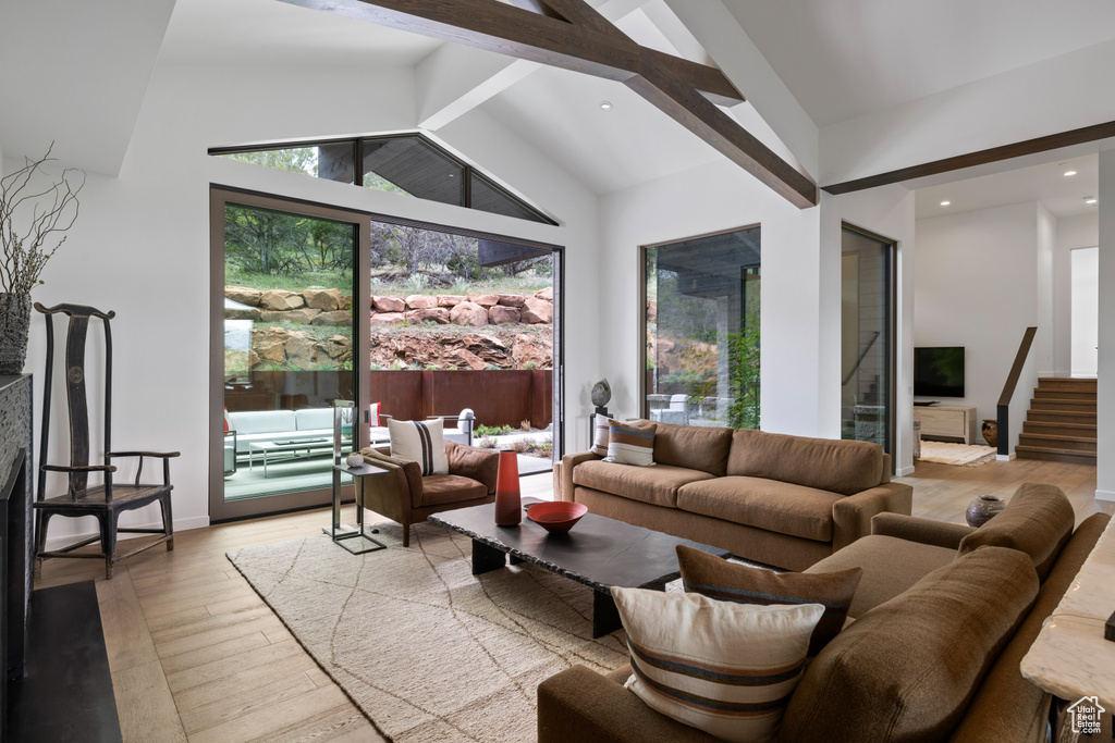 Living room with light wood-style flooring, beam ceiling, high vaulted ceiling, stairway, and recessed lighting