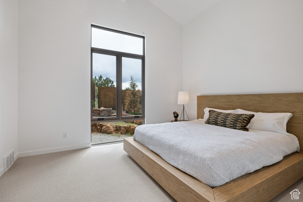 Carpeted bedroom with baseboards and high vaulted ceiling