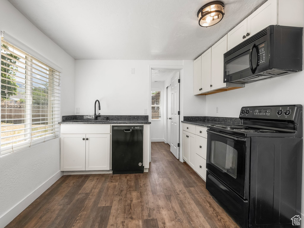 Kitchen with black appliances, dark wood-type flooring, and plenty of natural light