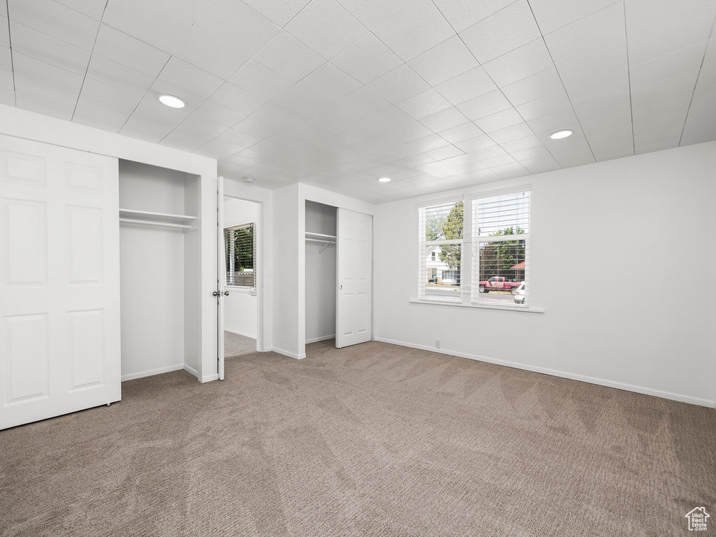 Unfurnished bedroom with two closets, carpet floors, baseboards, and recessed lighting