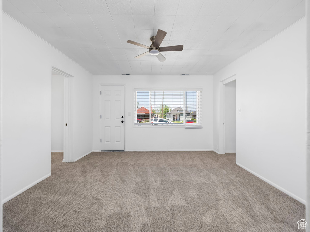 Unfurnished room featuring a ceiling fan, carpet, and baseboards