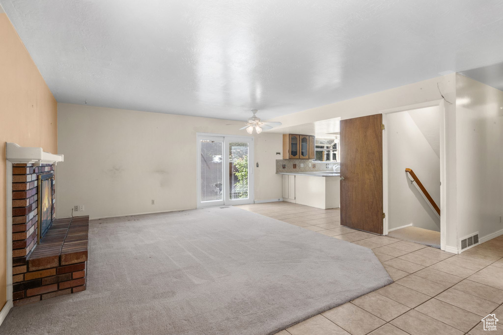 Unfurnished living room with light tile patterned flooring, a fireplace, ceiling fan, and baseboards