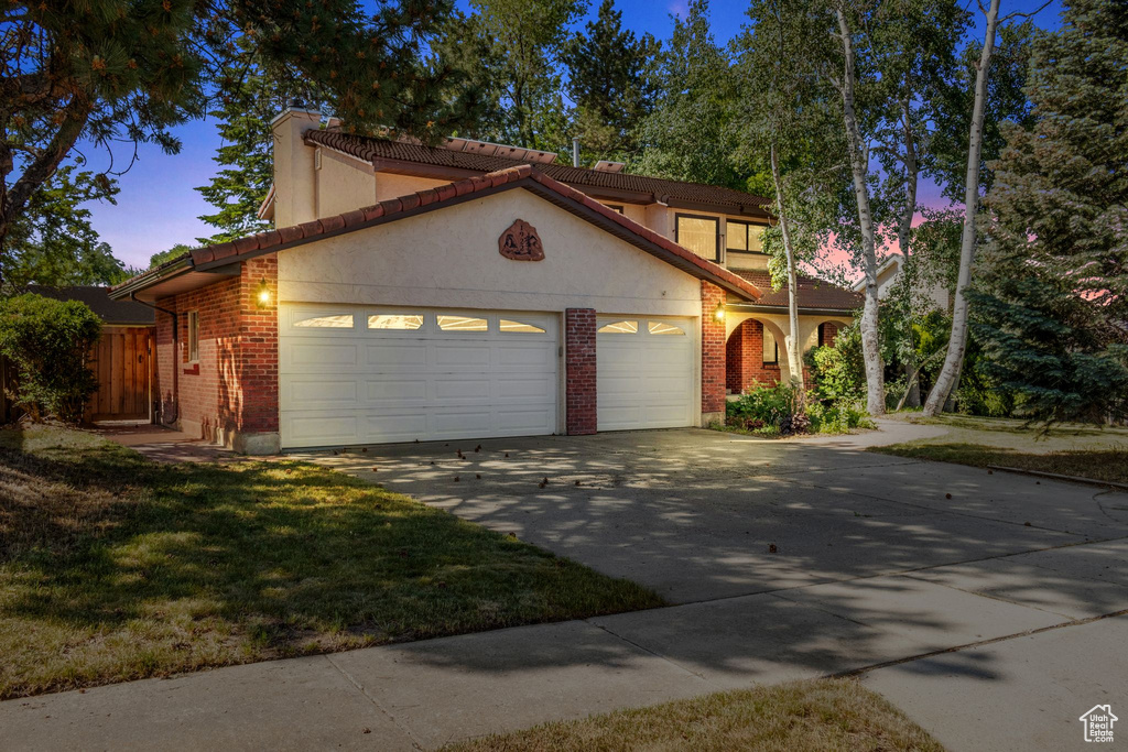 Mediterranean / spanish-style house featuring a garage, driveway, brick siding, and stucco siding