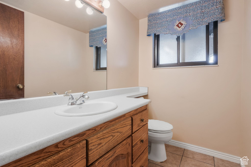 Bathroom featuring toilet, vanity, tile patterned flooring, and baseboards