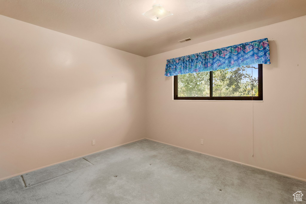 Carpeted spare room featuring baseboards