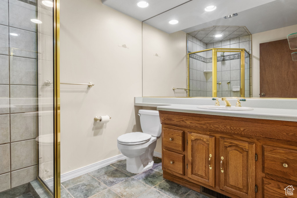 Bathroom featuring baseboards, toilet, vanity, and a shower stall