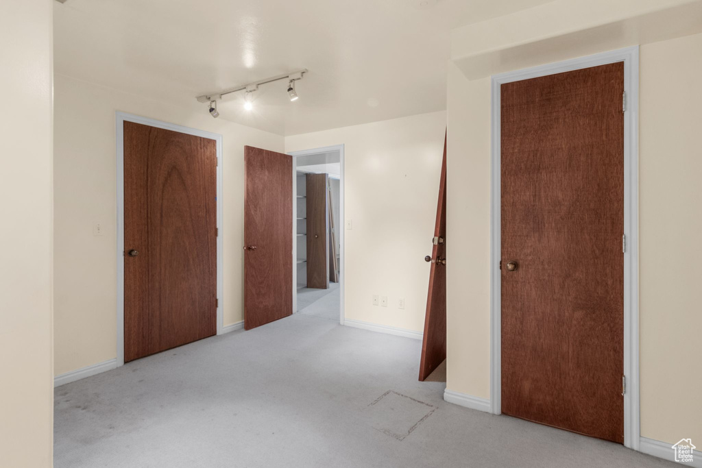 Unfurnished bedroom featuring carpet floors, rail lighting, and baseboards