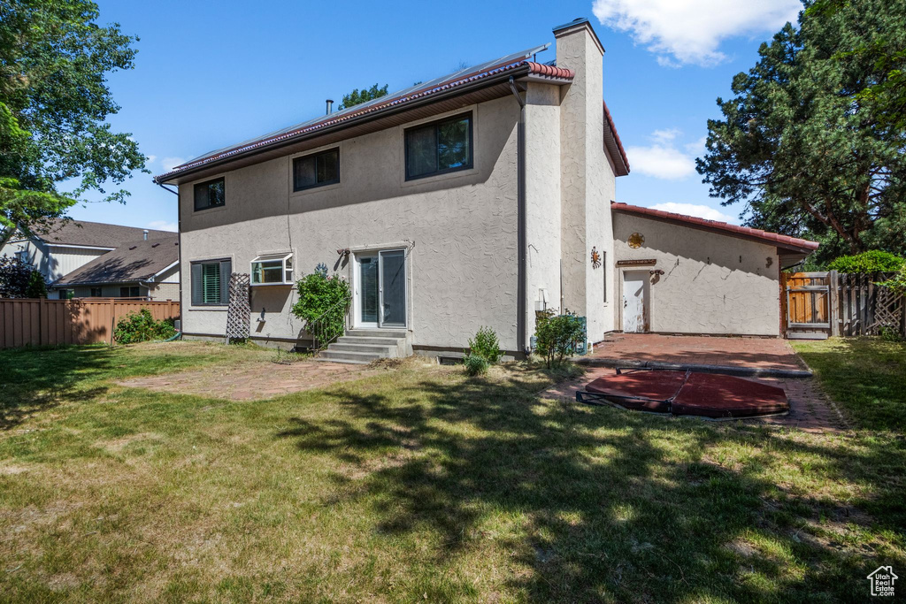 Rear view of property featuring entry steps, stucco siding, and a chimney