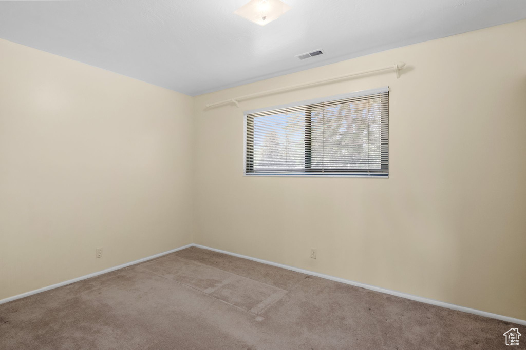 Unfurnished room featuring light carpet and baseboards