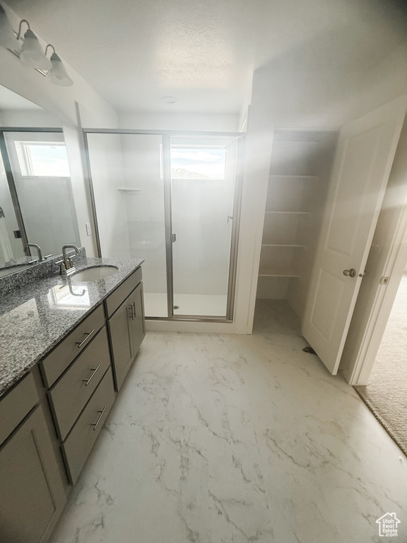 Bathroom with vanity, a shower stall, and marble look tile flooring