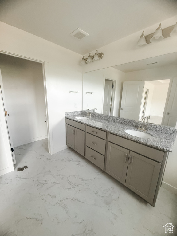 Bathroom featuring double vanity, marble finish floors, and baseboards