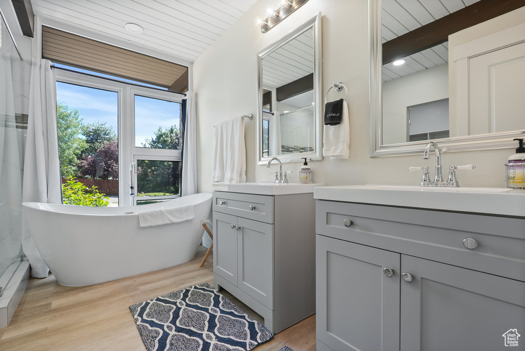 Full bathroom with vanity, wood finished floors, wooden ceiling with exposed beams, a soaking tub, and recessed lighting
